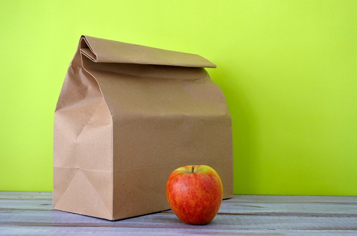 Almoço embalado em um saco de papel marrom com maçã vermelha