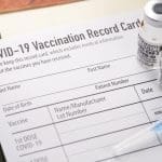 Covid-19 vaccination record card with vials and syringe