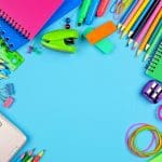 School supplies frame over a blue paper background with copy space