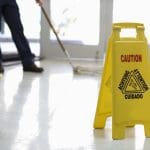 Senior Adult Janitor mops floor at entry to offices