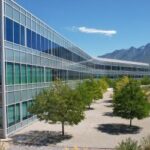 Glass building at the foot of tall green mountains