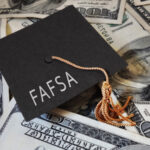 FAFSA (Free Application for Federal Student Aid) text on graduation cap and money - financial aid concept